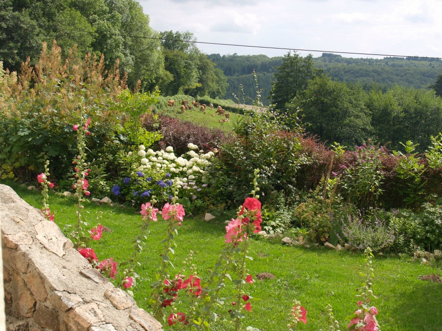 De tuin met stokrozen en hortensia's en het weidse uitzicht over de heuvels van de Morvan